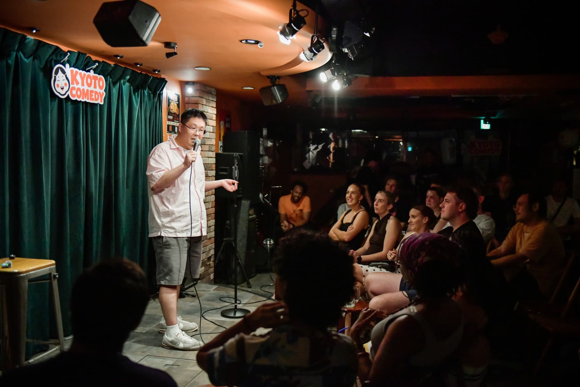 Comedian performing live on stage in front of the audience at a Kyoto Comedy show